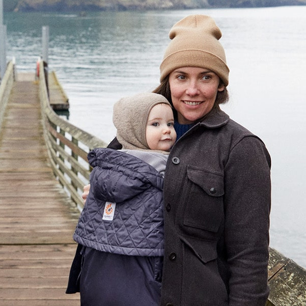 Women carrying baby with all weather cover nearby the sea